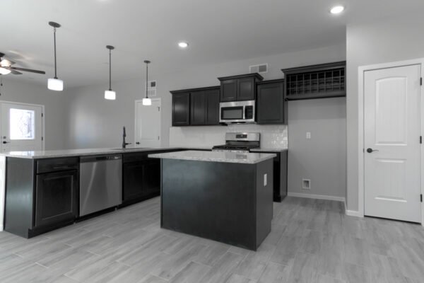 Open kitchen with island, dark cabinets, and stainless appliances