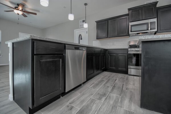Kitchen with dark cabinets and stainless steel dishwasher under island