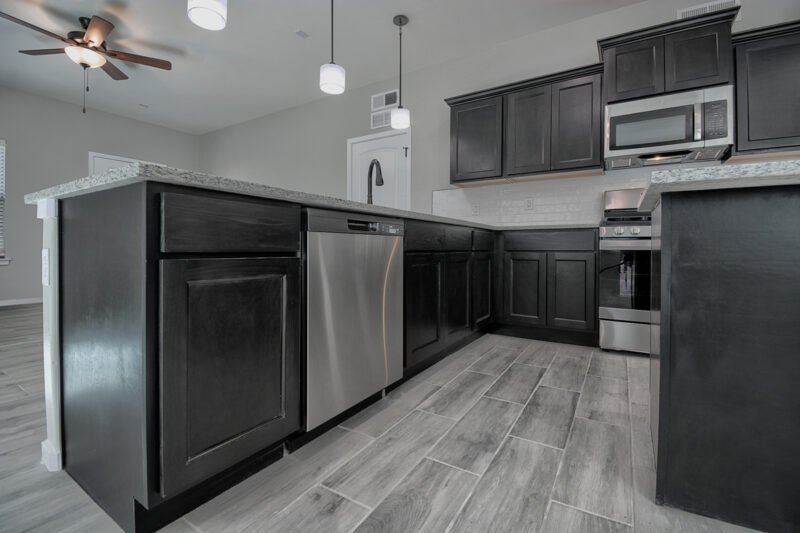 Kitchen with dark cabinets and stainless steel dishwasher under island