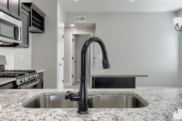 Close‑up of a black kitchen faucet over a sink with granite countertop