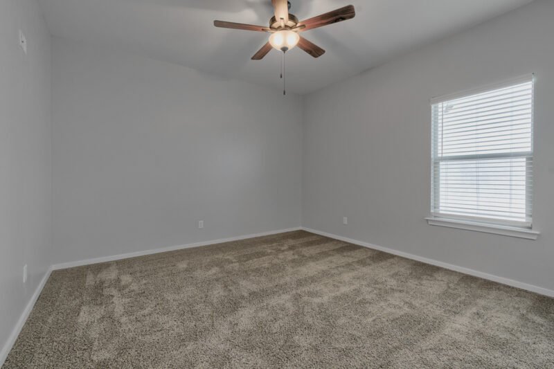 Master bedroom with large window and ceiling fan