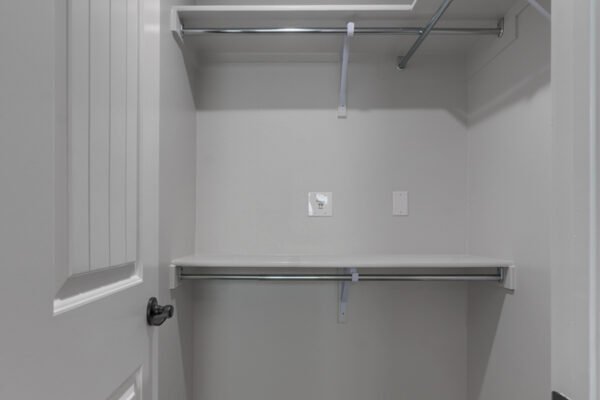 Walk‑in master bedroom closet with clothes rods and shelves