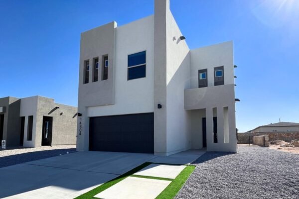 Modern two‑story stucco home exterior with garage and clear sky