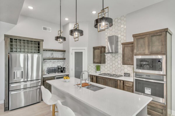 Modern kitchen with island, pendant lights, stainless fridge and wood cabinets
