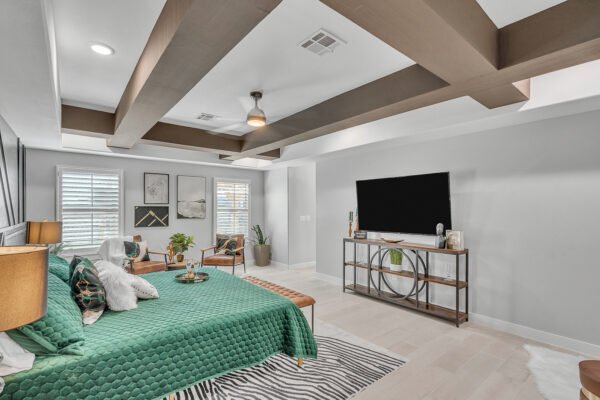 Spacious bedroom with green bedspread, seating area, and TV stand