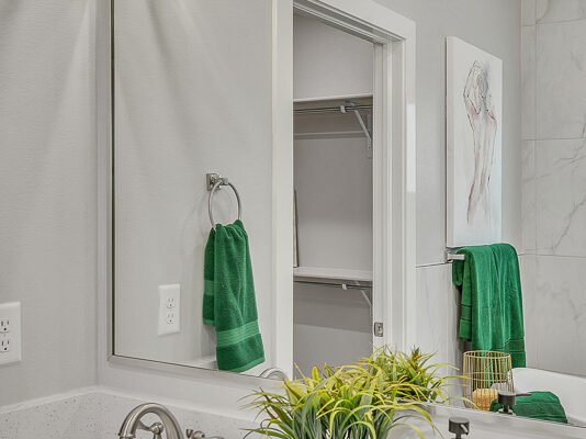 Bathroom vanity with sink, mirror, and green towels