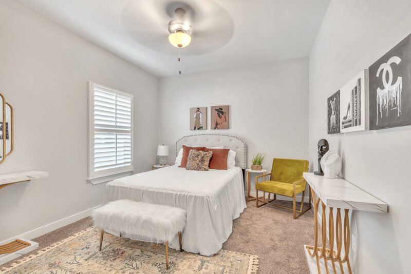 Bedroom with bed, green accent chair, and wall art