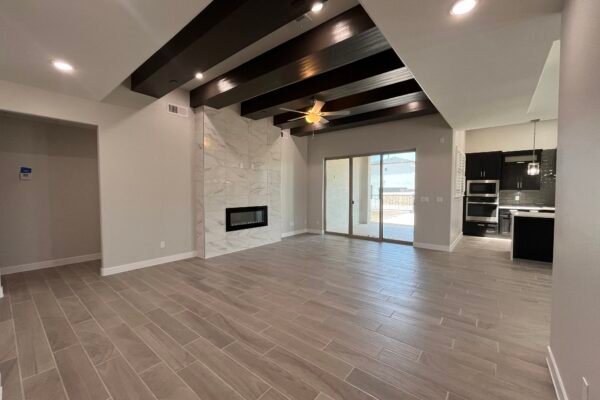 Open living room with fireplace, wood‑look floors, and ceiling beams