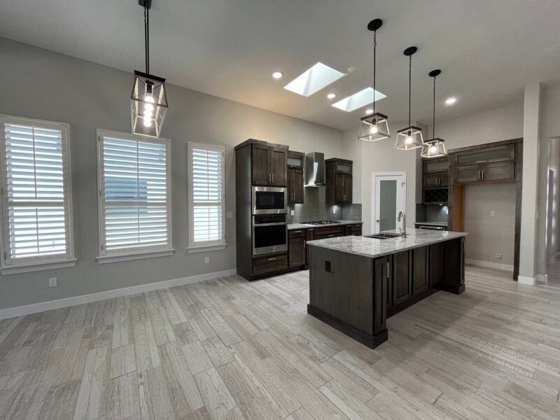 Modern kitchen with large island, dark wood cabinets, and skylights