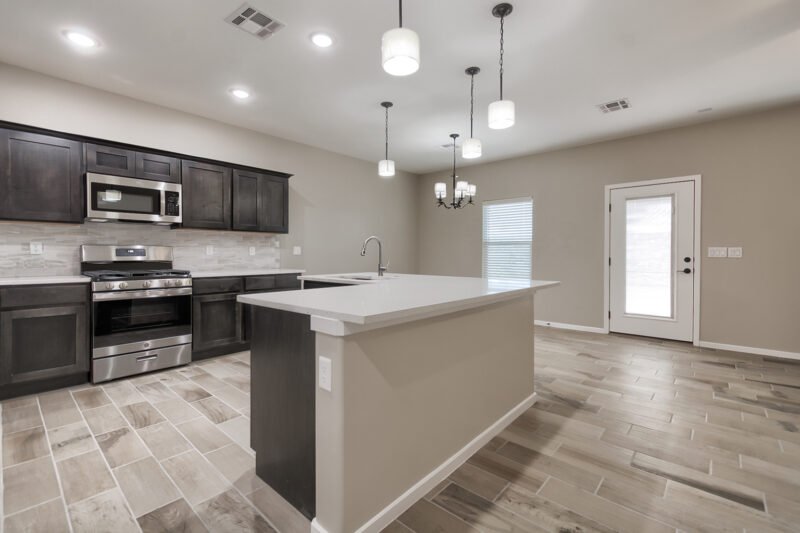 kitchen with a large island, dark cabinets, stainless appliances, and hanging lights