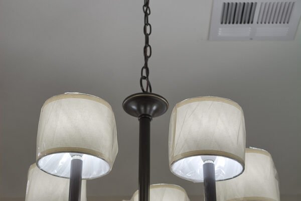A dining room chandelier with five fabric shades hanging from a chain