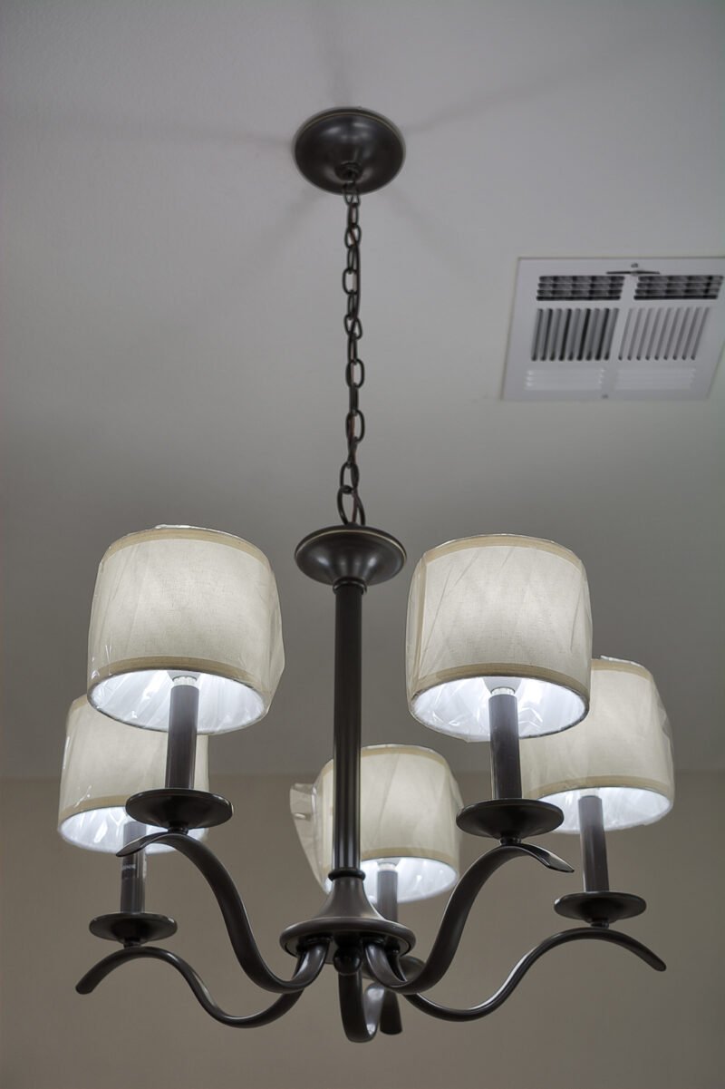 A dining room chandelier with five fabric shades hanging from a chain