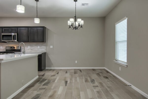 Empty dining area and kitchen in a new home with tile floor and hanging light fixture