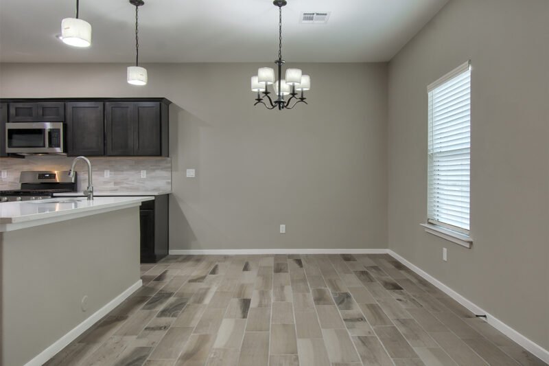 Empty dining area and kitchen in a new home with tile floor and hanging light fixture