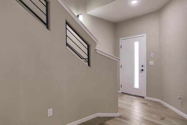 A home entryway with wood‑look tile floor and modern staircase railing