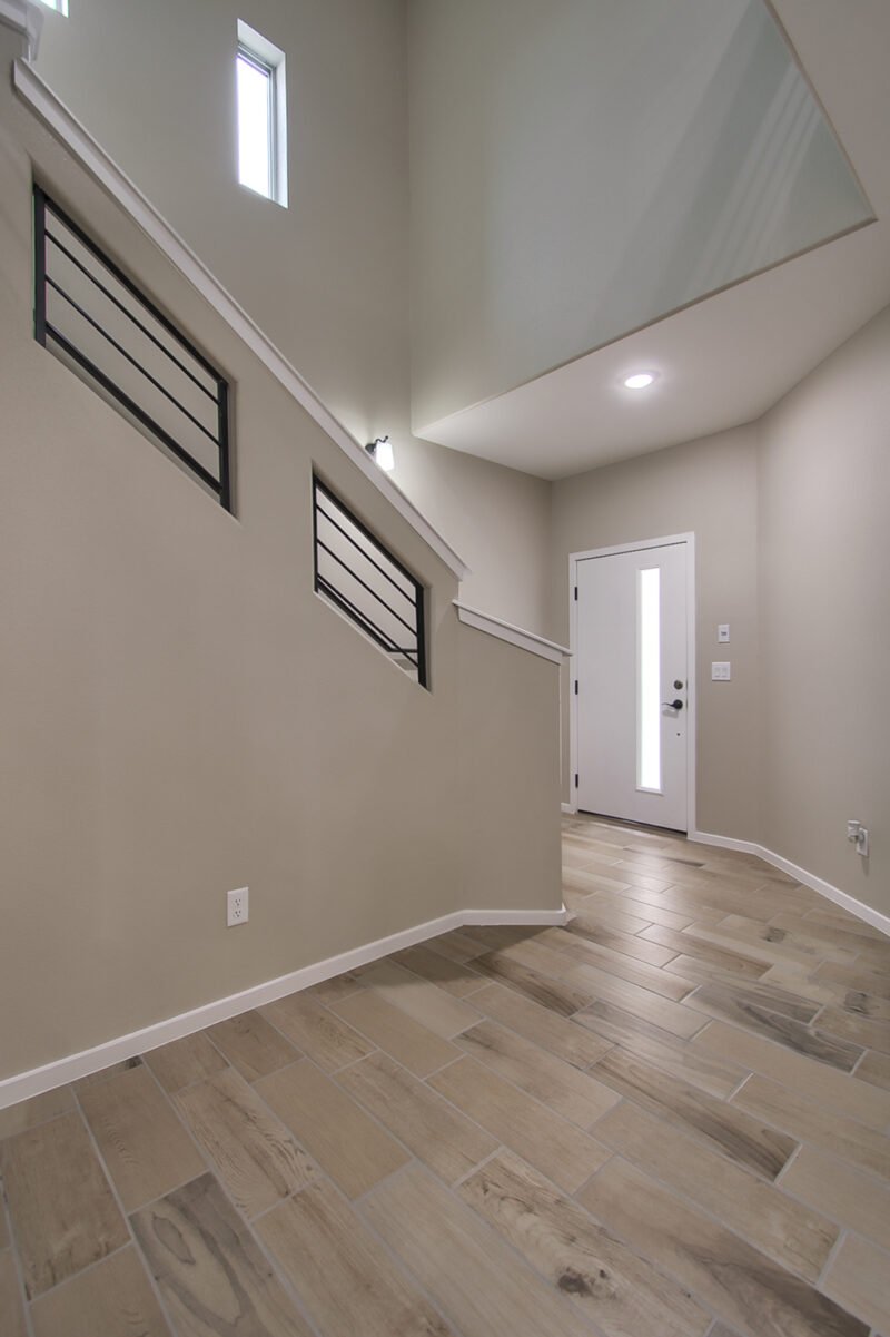A home entryway with wood‑look tile floor and modern staircase railing