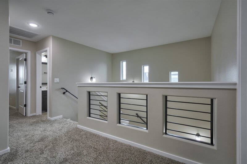 carpeted upstairs landing with a railing overlooking the staircase