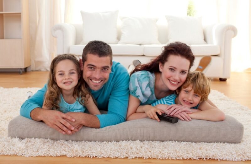 Smiling family of four lying on floor cushion in living room