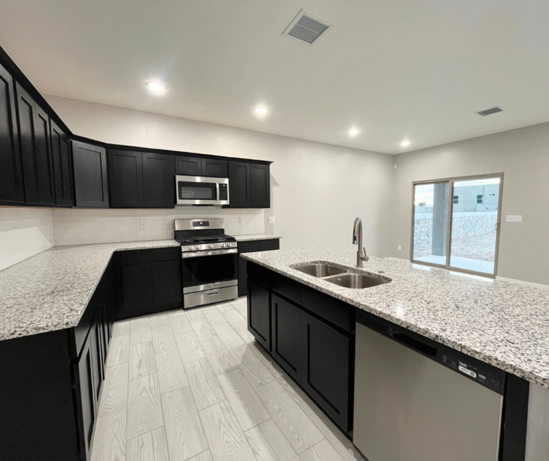 A modern kitchen with dark cabinets, granite island, stainless stove