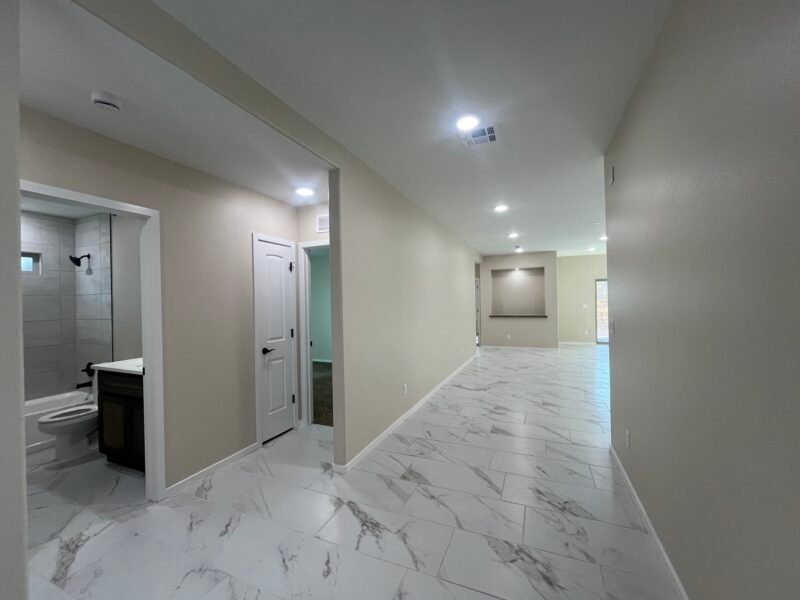 Hallway interior with tile floor, bathroom doorway, and open living area