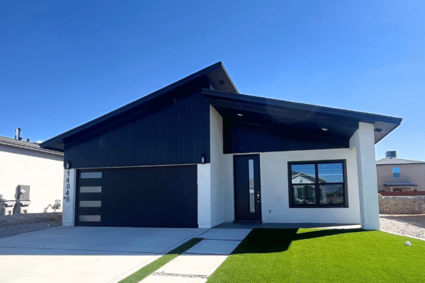 Modern single‑story house exterior with black garage door and green lawn